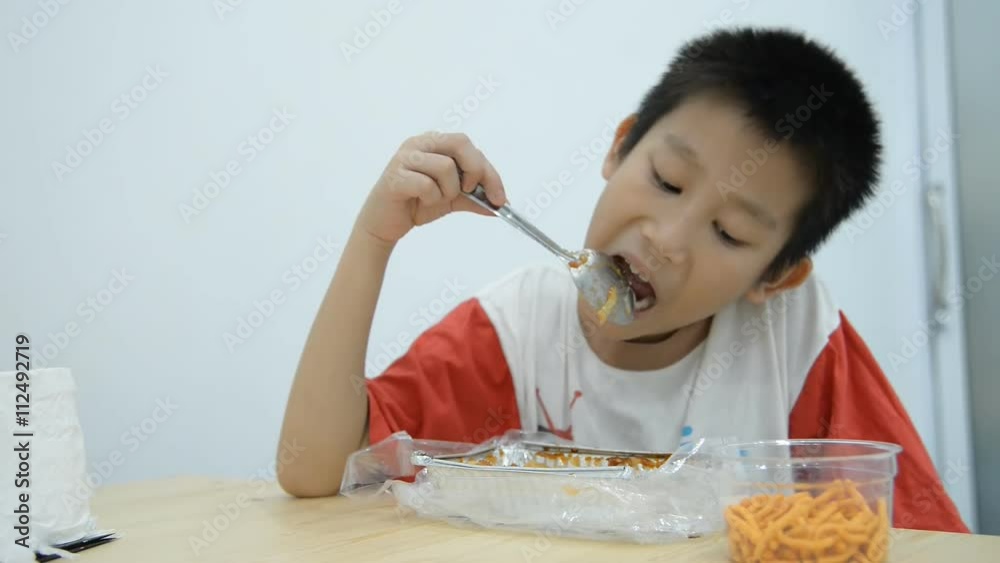 Asian boy eating homemade Lasagna at home