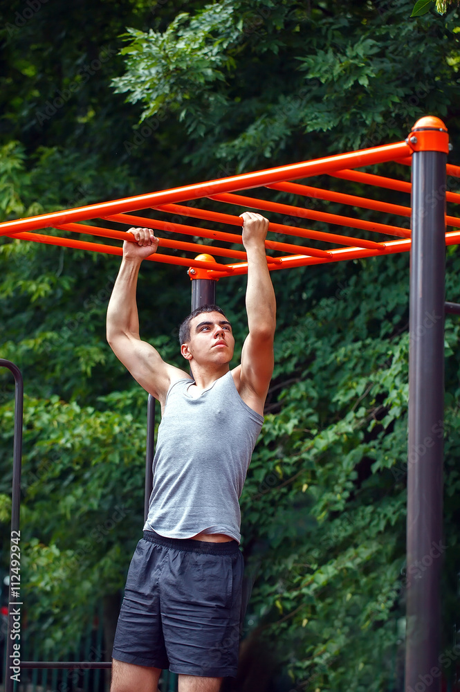 Muscular man doing pull-ups on horizontal bar Muscular man doing pull-ups on horizontal bar