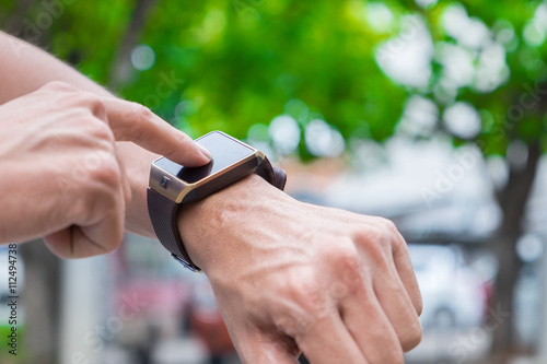 man using his smart watch app. Close-up hands with bokeh back gr