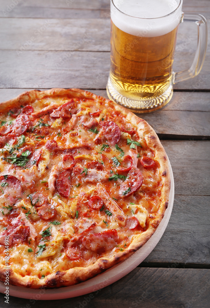 Φωτογραφία Tasty pizza and glass of beer are on wooden table, close up