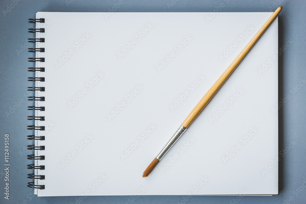 Paintbrush on blank drawing paper book with wooden background, vintage style Paintbrush on blank drawing paper book with wooden background, vintage style