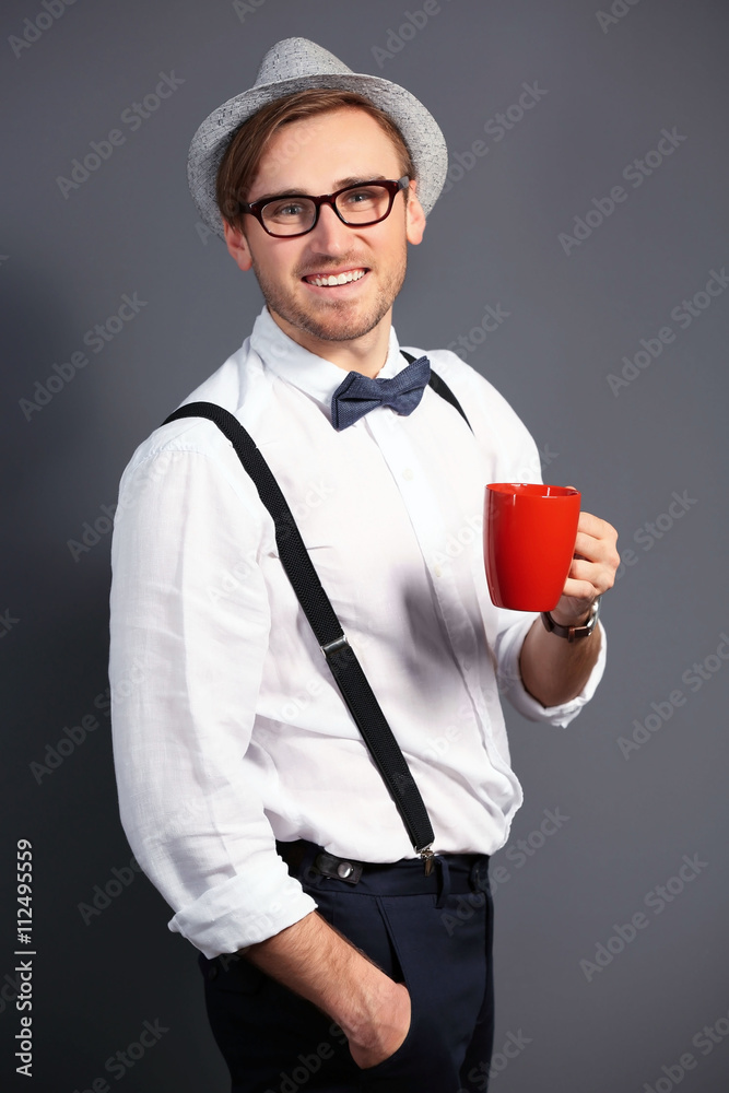 Young handsome man with a cup of coffee on dark grey background