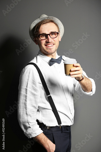 Young handsome man with a cup of coffee on dark grey background © Africa Studio
