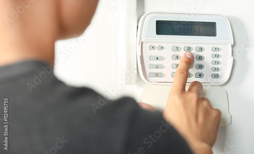 Man pressing the code on a house alarm photo