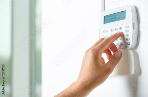 Male hand pressing the code on a house alarm photo