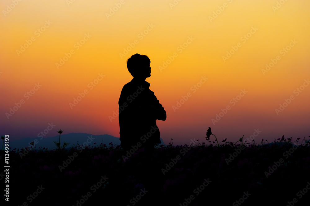 Silhouette of man posing at sunset sky background.