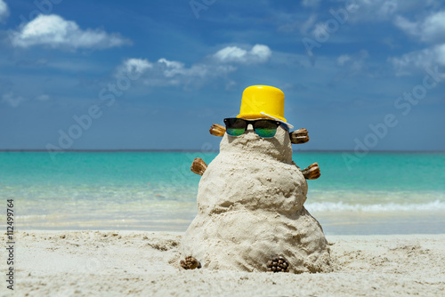Snowman made from sand on the tropical beach on background of paradise sea