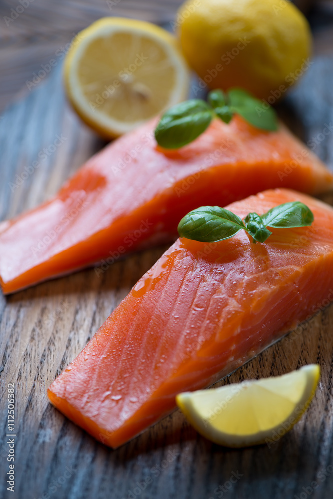 Closeup of smoked trout fillet with lemon and green basil leaves