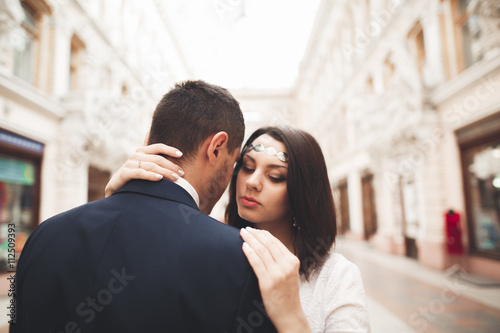 Beautiful wedding couple, bride, groom kissing and hugging against the background of old building
