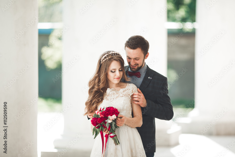 Beautiful couple, bride and groom posing near big white column Beautiful couple, bride and groom posing near big white column
