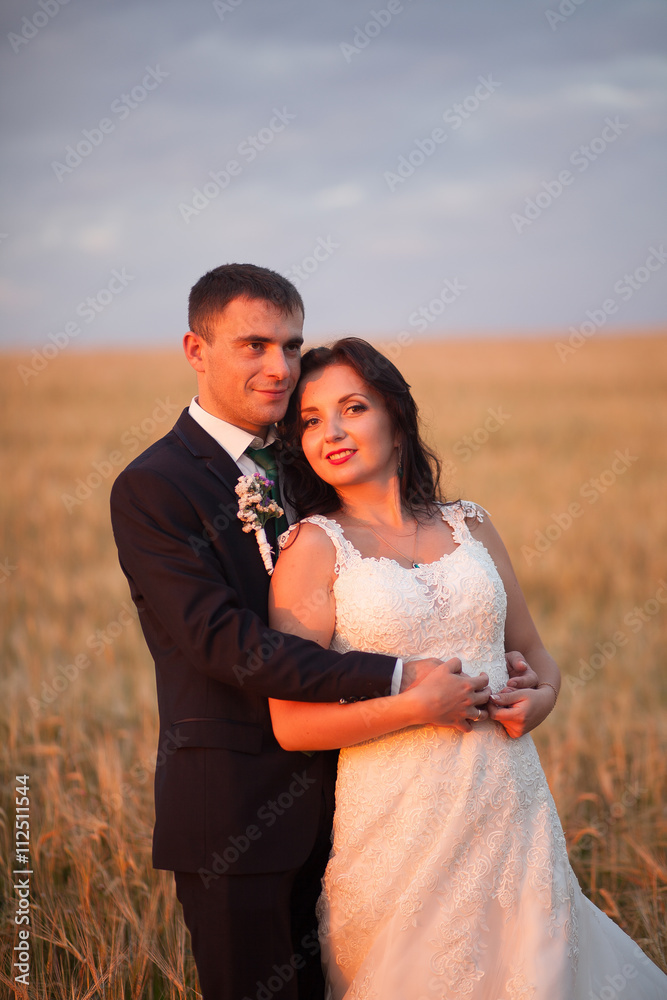 Beautiful romantic wedding couple of newlyweds hugging in park on sunset Beautiful romantic wedding couple of newlyweds hugging in park on sunset