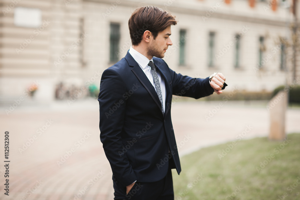 Confident businessman looking on his wrist watch in suit Confident businessman looking on his wrist watch in suit