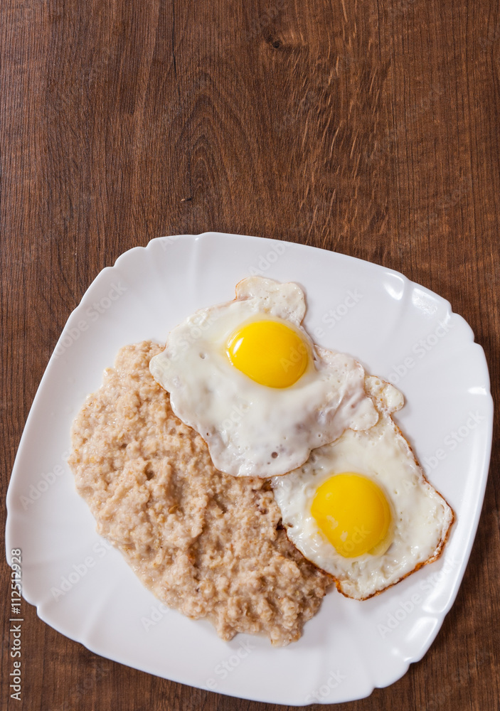 oatmeal porridge with fried egg in a plate on wooden table oatmeal porridge with fried egg in a plate on wooden table
