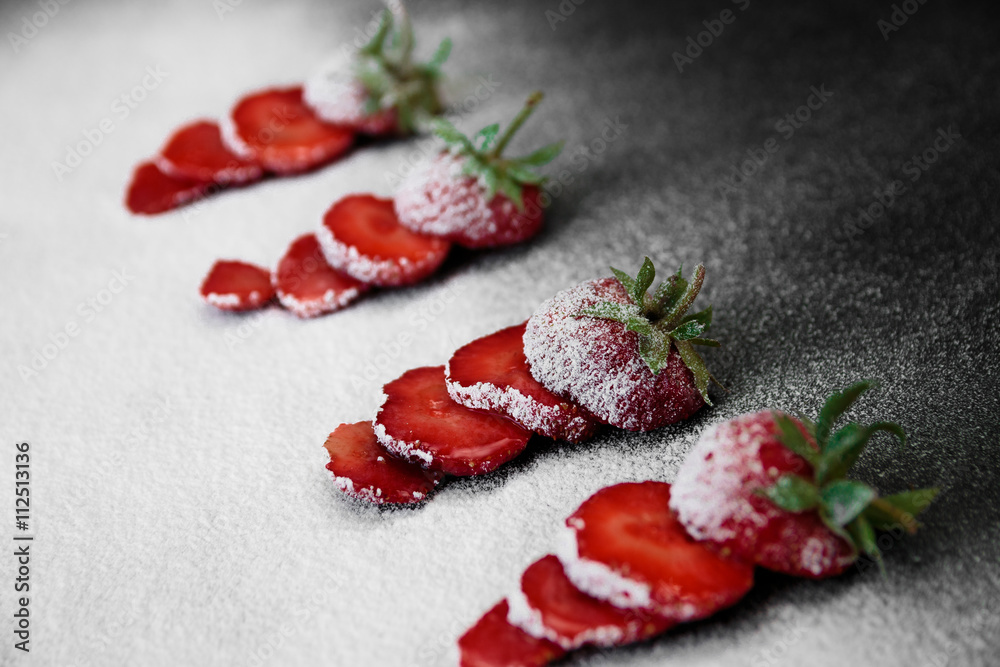 Beautiful sliced strawberries powdered sugar on black backfround. Closeup. Copy space Beautiful sliced strawberries powdered sugar on black backfround. Closeup. Copy space