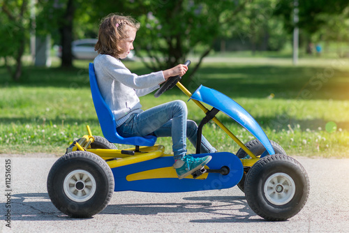 Little girl riding on pedal karting.