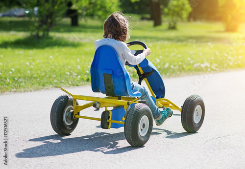 Little girl riding on pedal karting.