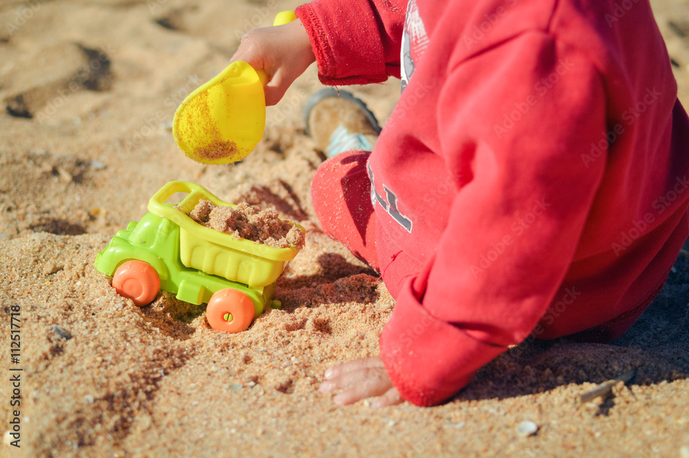 Kid having fun outdoors happy playing with his truck toys on a sunny summer day background sandy Kid having fun outdoors happy playing with his truck toys on a sunny summer day background sandy