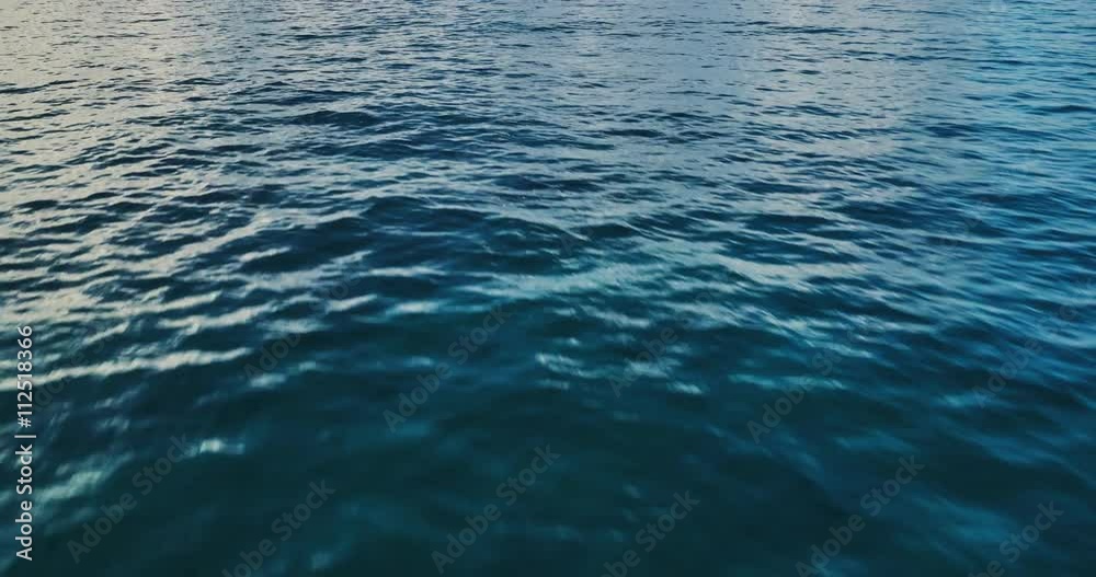 Flying over ocean at sunrise, aerial view flying over water into clouds