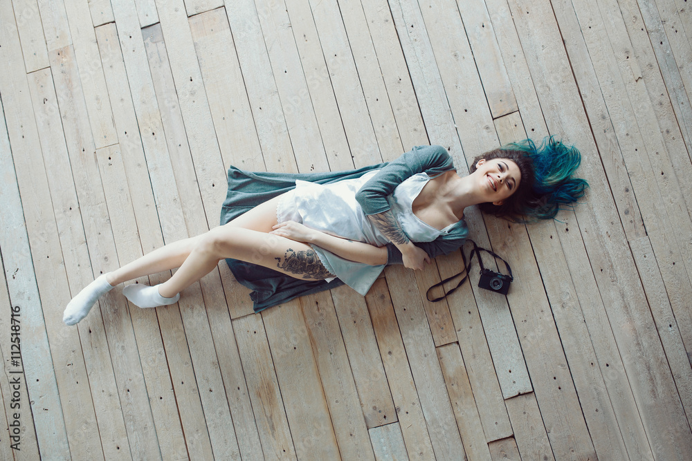 Naklejka premium Beautiful carefree young casual woman lying on the wooden floor