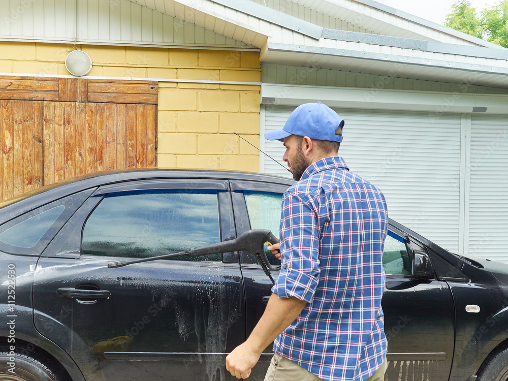 Man washing his black car near house. Man washing his black car near house.