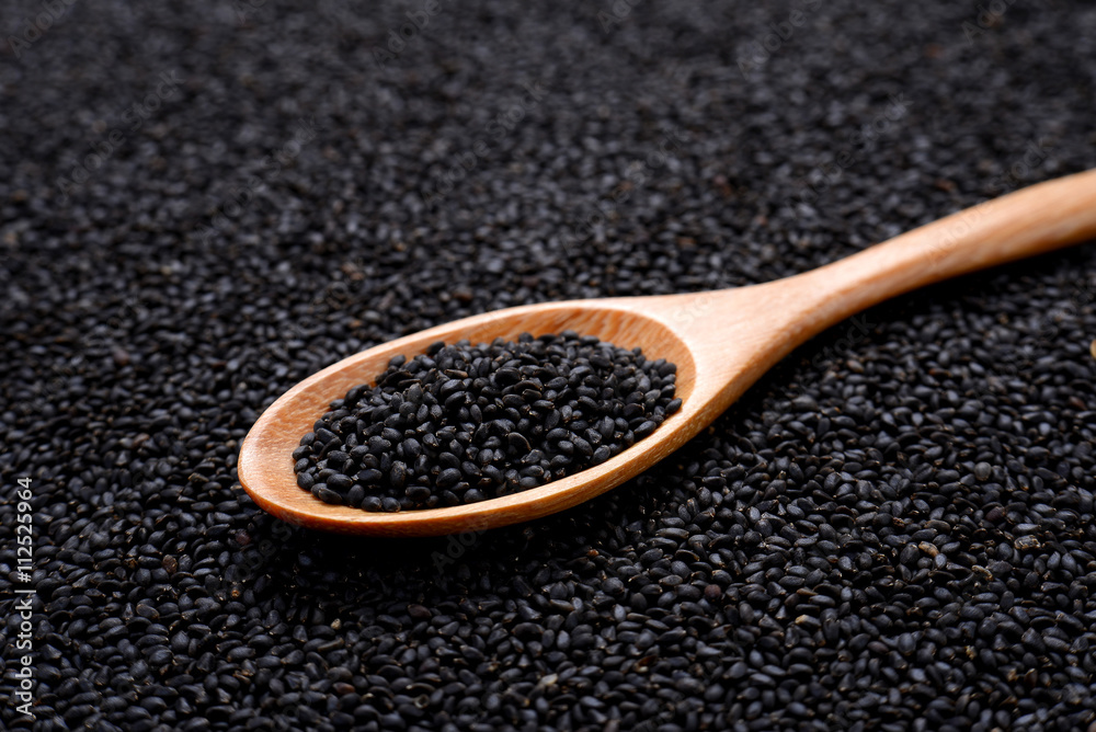 Black sesame in wooden spoon on sesame background. Black sesame in wooden spoon on sesame background.