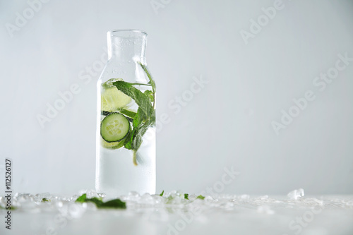 Vintage glass bottle filled with cold fresh cucumber mint lime lemonade like mojito witount alcohol, ideal drink for summer isolated on table with melted ice