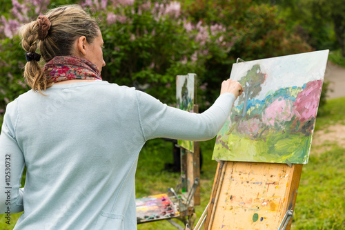 Canvas Print Woman painter panting her masterpiece in the garden