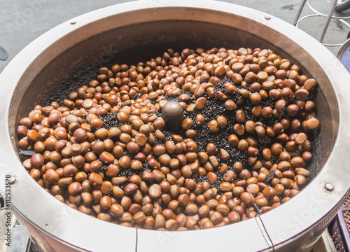 Roasting chestnut in rotary machine at Bangkok chinatown market, Thailand. street food photo