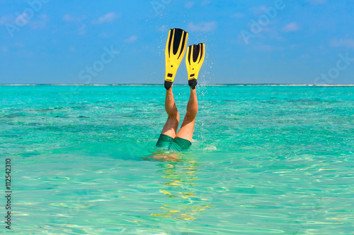 Men dive snorkeling in clear water with yellow flippers