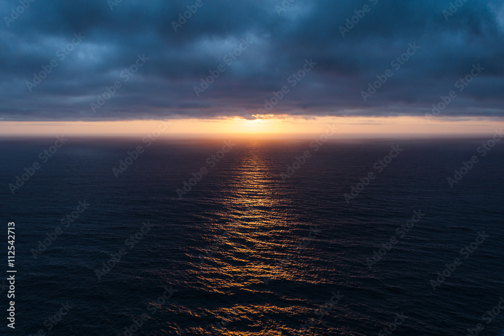 The sunlight pierced the dark blue clouds and lit up the Atlantic Ocean.