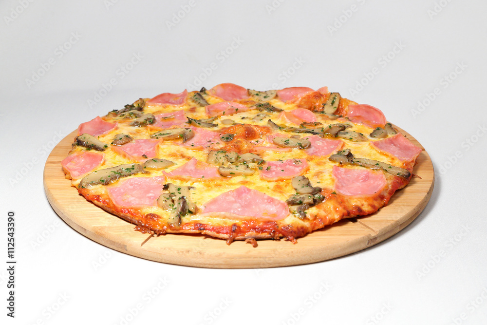 pizza with ham on a round pedestal made of wood