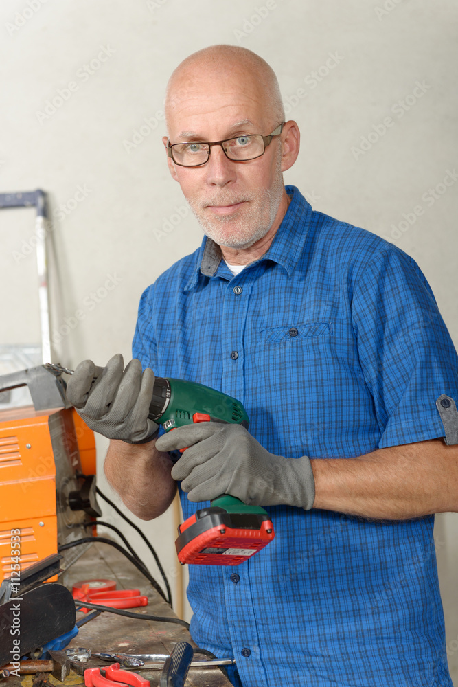mature man with a drill in his workshop mature man with a drill in his workshop