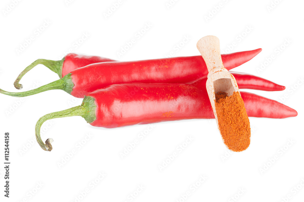 Three pods of chili and ground paprika in a wooden spoon Three pods of chili and ground paprika in a wooden spoon