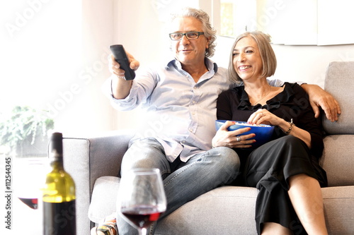 Aged couple eating popcorn and watching tv
