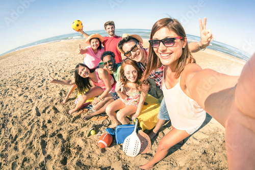 Group of multiracial happy friends taking selfie and having fun at beach - Friendship concept with summer sports equipment 