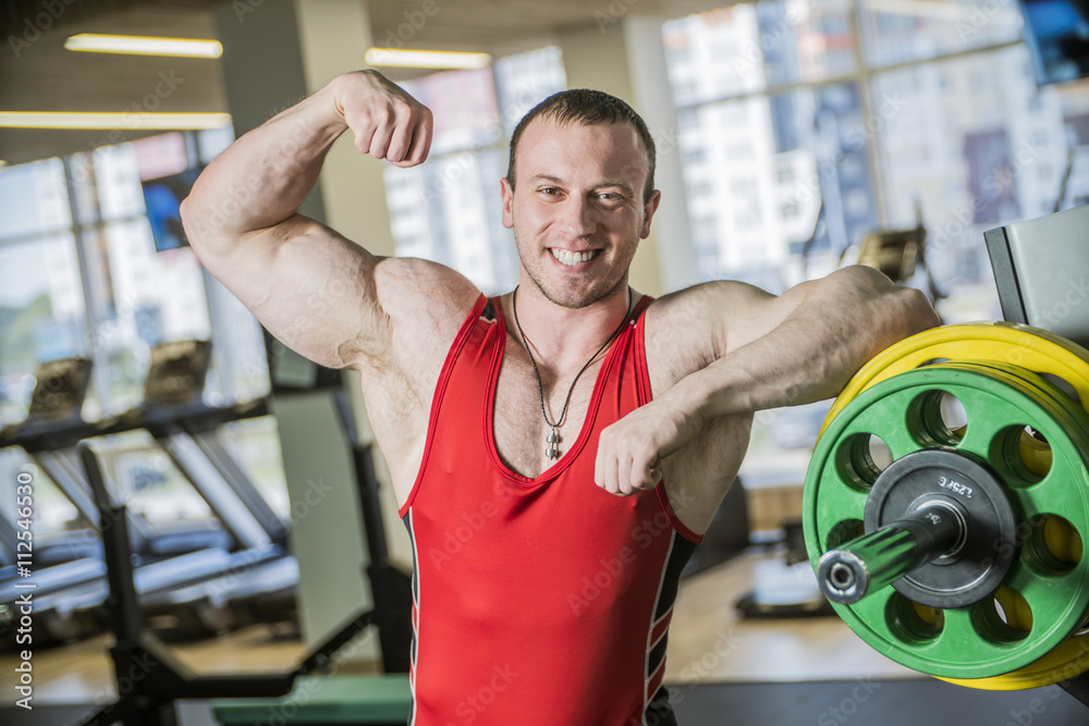man is engaged in fitness bodybuilder posing shows biceps and smiling