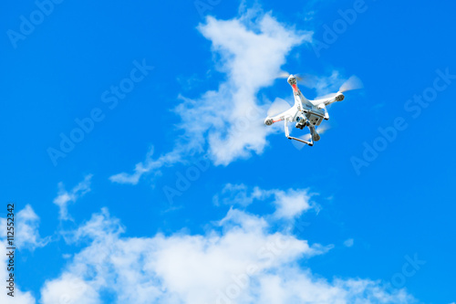 White quadrocopter in blue cloudy sky, drone