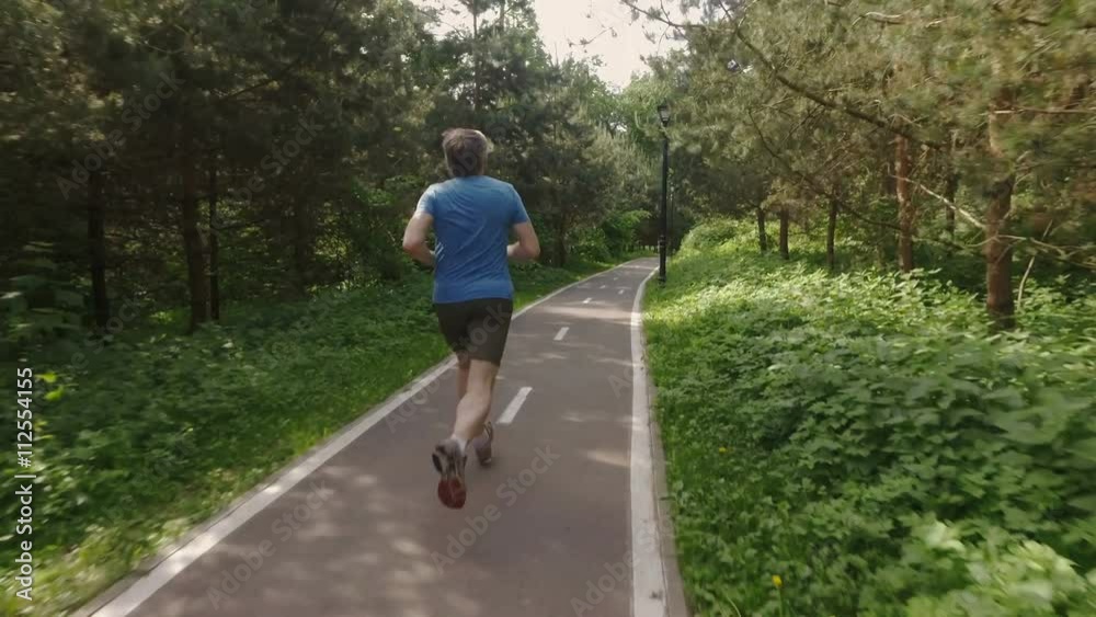 Adult man running jogging outdoors in a forest nature on a forest trail and enjoying it and looking happy Adult man running jogging outdoors in a forest nature on a forest trail and enjoying it and looking happy