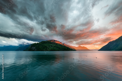 Sunset over mountains and lake. Special bright colors before storm, windy