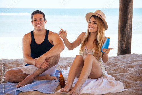 Newlyweds putting sunblock on at the beach