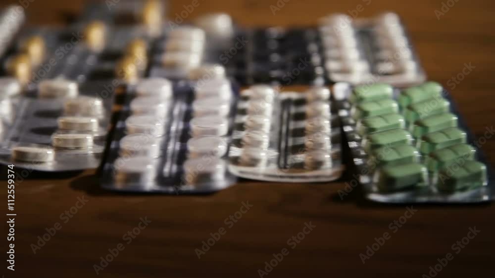 Package of medicine pills for better health.Medicine.Pills and capsules in aluminum container on wooden table.Many various pills lying on the table.Pile of Drugs Closeup. Package of medicine pills for better health.Medicine.Pills and capsules in aluminum container on wooden table.Many various pills lying on the table.Pile of Drugs Closeup.