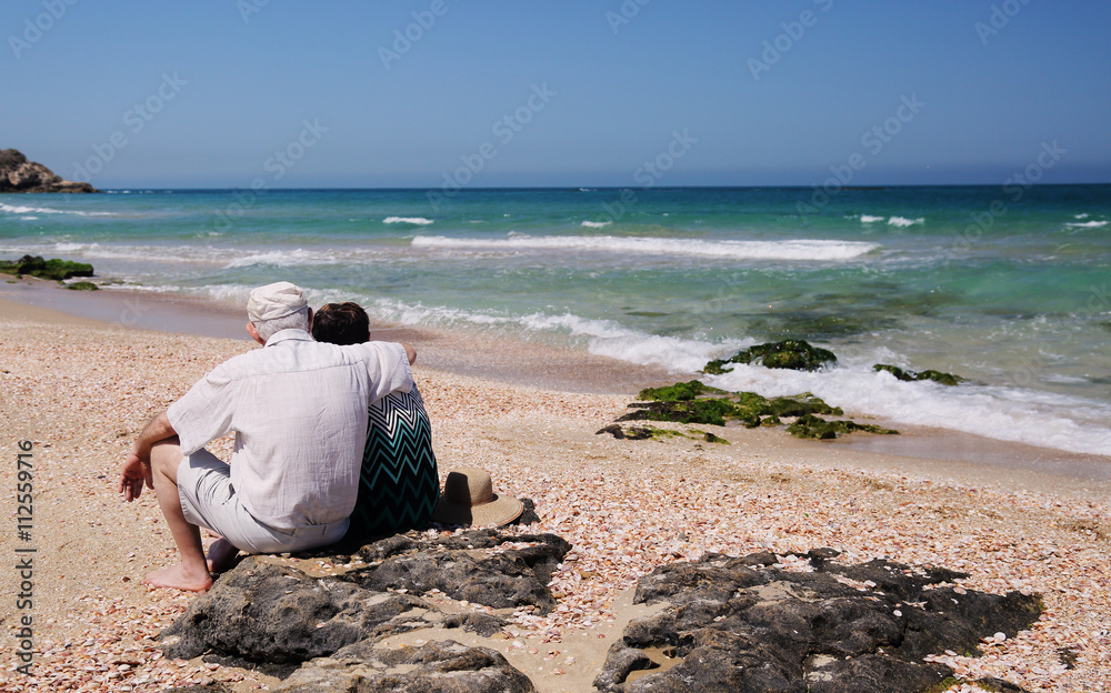 senior couple sitting on the beach
