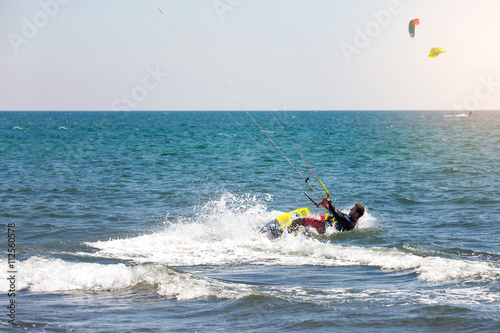 Athletic man riding on kite surf board on a sea waves