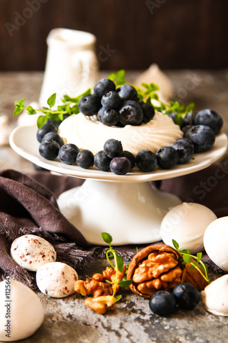 meringue pavlova cake with fresh blueberries and walnuts on dark