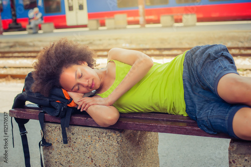 Female backpacker tourist napping on a bench