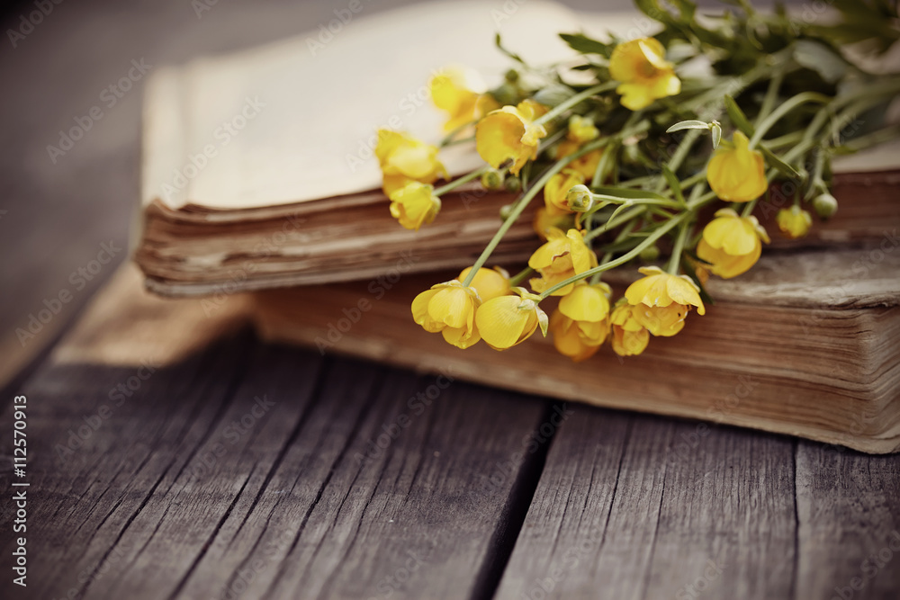 Old open book and bouquet of yellow buttercups. Old open book and bouquet of yellow buttercups.