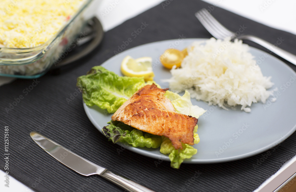 Fish atlantic salmon with salad and grated radish. The main meal for dinner with fish on the blue plate. Fish atlantic salmon with salad and grated radish. The main meal for dinner with fish on the blue plate.