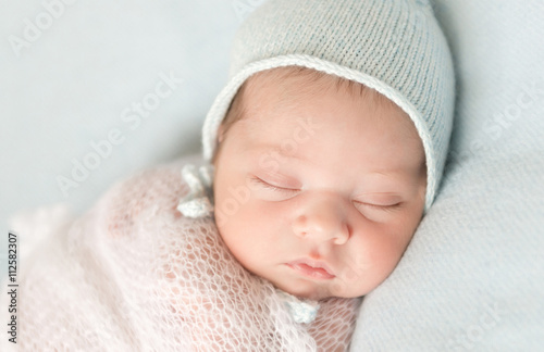 beautiful sleeping newborn baby in hat and wrapped close-up