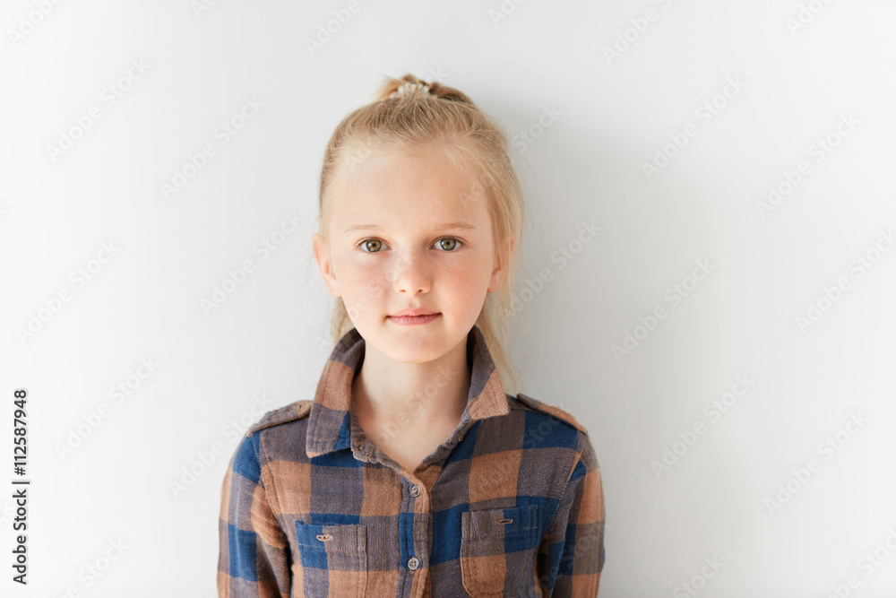Cute blond girl with posing on white background. Portrait of relaxed kid with nice kind look. Calm and pretty little Caucasian girl with pony-tail in brown shirt. Childish innocence Cute blond girl with posing on white background. Portrait of relaxed kid with nice kind look. Calm and pretty little Caucasian girl with pony-tail in brown shirt. Childish innocence