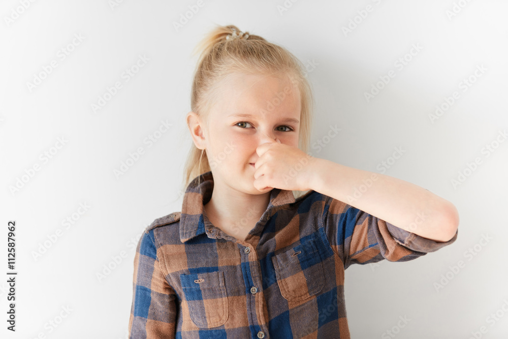 Little Girl In Checked Brown Shirt Pinching Her Nose Because Of Bad